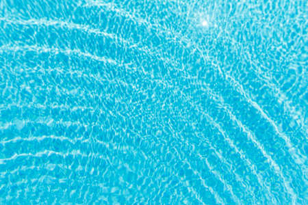 Surface of blue shining swimming pool water ripple and sun reflection. Perfect as a background for...