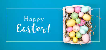 Multicolor eggs in a white tray. Creative Easter concept. Modern solid turquoise background. Color of the year inspired. Horizontal, banner wide screen formatの写真素材
