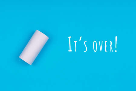 Toilet paper empty sleeve on the bright blue background with Its over wording. Coronavirus pandemic panic shopping concept. Bright monochrome dropの写真素材