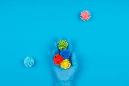 Hand in disposable glove with plastic balls viruses on the blue. Epidemic, seasonal viruses, social isolation, shutdown, coronavirus COVID-19 concept. Ready to use design easy to cut to bannerの写真素材