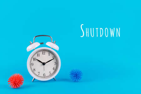 Alarm clock and plastic balls aka viruses on the blue background with Shutdown wording. Epidemic, social isolation, coronavirus COVID-19 concept. Option with textの写真素材