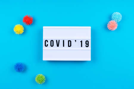Lightbox with COVID-19 wording and plastic balls aka viruses on the blue background. Epidemic, social isolation, coronavirus COVID-19 concept. Horizontal with copy spaceの写真素材