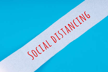 Toilet paper roll with Social distancing wording on the bright blue background. Coronavirus COVID-19 pandemic panic shopping, social distancing concept. Bright monochrome dropの写真素材