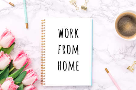 Pink tulips with festive stationary and coffee on white marble background with Work from home wording. Feminine job, gender equality, home office and career concept. Copy space Top view. Horizontalの写真素材