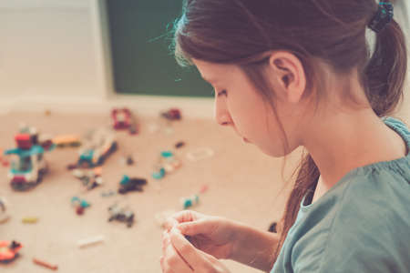 Elementary school student connects two blocks during time at home playing with constructor set. Leisure time, creativity development, stay at home isolation time conceptの写真素材