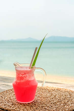 Colorful watermelon mocktail at the beach bar with sea background. Vacation, get away, summer outing conceptの写真素材