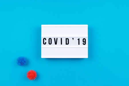 Lightbox with COVID-19 wording and plastic balls as viruses on the blue background. Epidemic, social isolation, coronavirus COVID-19 concept. Horizontal with copy spaceの写真素材
