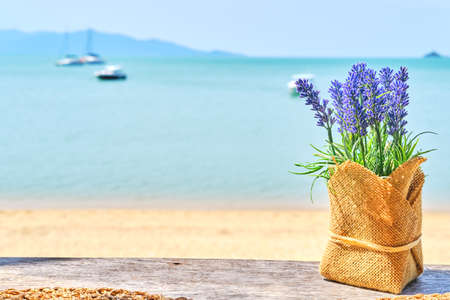 Lavender decoration table accent at the beach bar with sea background. Vacation, get away, summer outing conceptの写真素材