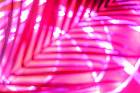 Futuristic blurred neon drop in red and pink with traces of palm greenery, place for text, easy cut to bannerの写真素材