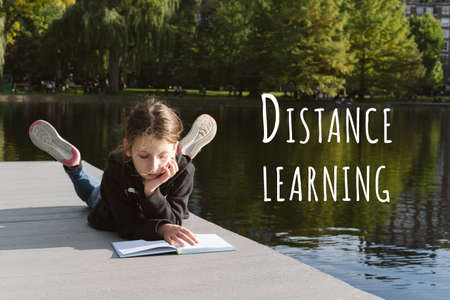 Girl enjoyes reading by the pond, Distance learning wording. Relaxation and self education conceptの写真素材