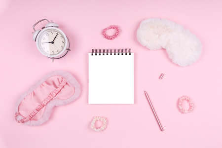 Notepad with cute fluffy sleep masks and pink accessories. Sleep management and optimization, beauty sleep and sleep log concept. Place for textの写真素材