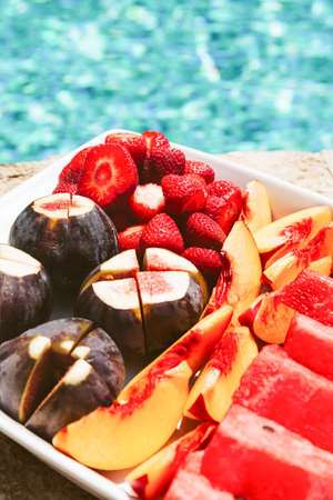 Exotic tropical fruit plate on the pool edge. Healthy treat, luxury resort vacation conceptの写真素材