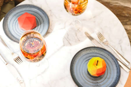 Blooming flower tea served in a wine glass and futuristic cake, white marble table at the trendy...