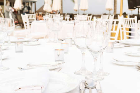 Festive serving with glasses for an outdoor celebration with garland lamps and palms at the...
