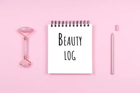 Jade face roller and white journal with Beauty log wording. Beauty time, selfcare and beauty accessories, beauty log conceptの写真素材