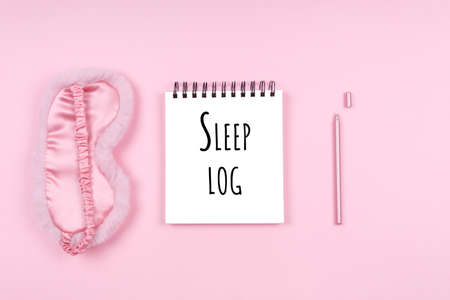 Note pad with cute flaffy sleeping mask and stylish pen with Sleep log wording. Beauty time, selfcare and sleep log, feminine time management and planning conceptの写真素材