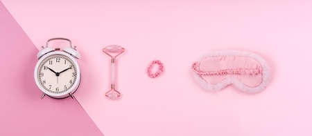 Pink drop with cute fluffy sleep mask, jade roller, watch and pink accessories. Sleep management and optimization, beauty sleep, beauty and sleep log concept. Place for text, banner formatの写真素材