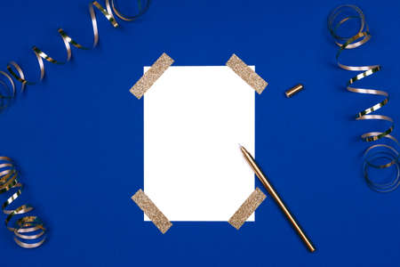 Isolated white card mock up with festive golden ribbons. Flat lay background in gold and classic blue colors for any celebration and party occasion. Horizontalの写真素材