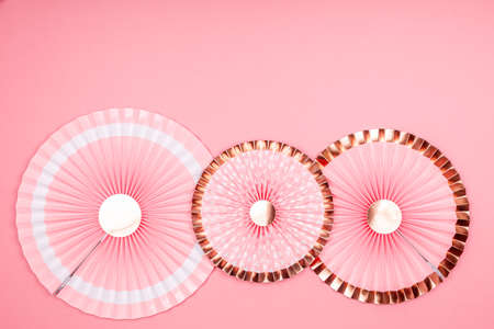Pink and golden paper fans on pink drop. Party, decorations, celebration backdrop with place for textの写真素材