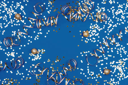 Holiday background with confetti, balls and ribbons on classic blue. Seasonal Christmas celebration backdropの写真素材