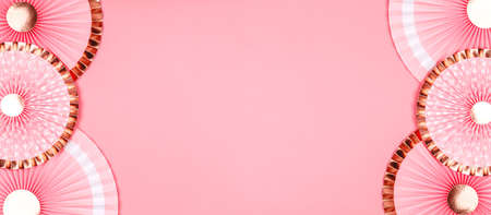 Pink and golden paper fans on pink drop. Party, decorations, celebration backdrop with place for textの写真素材
