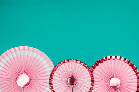 Pink and golden paper fans on turquoise drop. Party, decorations, celebration backdrop with place for textの写真素材