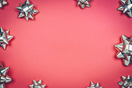 Silver gift bows on the red background with place for text. Traditional celebration and gift giving conceptの写真素材