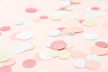 Multicolor pink, gold and white confetti on the light peach pink background, holiday celebration backdrop, Flat lay style with place for textの写真素材