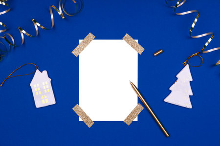 Isolated white card mock up with festive golden ribbons and Christmas toys. Flat lay background in gold and classic blue colors for any celebration and party occasion. Horizontalの写真素材