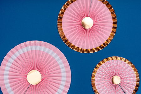 Pink and golden paper fans on classic blue drop. Party, decorations, celebration backdrop with place for textの写真素材