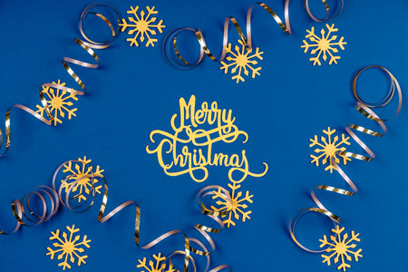 Holiday background with Merry Christmas wording, golden snowflakes, and ribbons on classic blue. Holiday celebration card conceptの写真素材