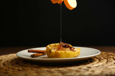 On the plate is a baked pumpkin, an apple and a glass jar with honey, near cinnamon, anise, mint....