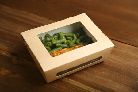 Delivery of food at home. Healthy and proper nutrition, grilled fish and green beans in a cardboard...