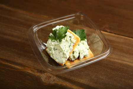 Delivery of food at home in a container of cottage cheese with herbs is decorated with parsley on a cracker. Low-calorie cookies. A healthy diet for those who control their bodyの写真素材