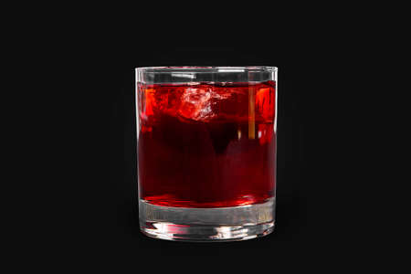 Single-color transparent cocktail, refreshing in a low glass with ice cubes with taste of berries, cherries, strawberries, grapefruit. Side view Isolated black background. Drink for the menuの写真素材