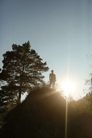 Summer silhouette of a man on top of a mountain, reached the top, overcame himself, sunlight from behind, free space for a signature. Achievement, overcoming, career growth is abstract.の写真素材