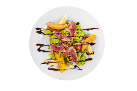 Salad with roast beef with fried potatoes, eggs, lettuce, tomatoes balsamic vinegar, sauce on plate, white isolated background, view from aboveの写真素材