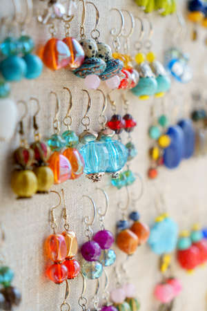 Many colorful earrings for sale at outside street market hanging on canvas, side view, verticalの写真素材