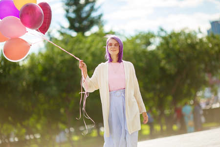 Young lady with purple hair, in pink glasses, white sweater pink t-short and blue skirt, with bunch...