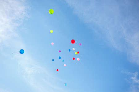 A several wonderful coloured air balloons are flying into the blue sky with little clouds on it