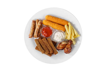Hot appetizer croutons from rye bread, set of sausages, cheese sticks in breading, chicken pieces, French fries, mayonnaise sauce, tar-tar, ketchup on plate, white isolated background view from aboveの写真素材