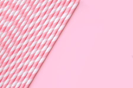 Banner with pastel paper straws with white stripes on soft pink background. Festive zero waste concept. Flat lay style with copy space.の写真素材