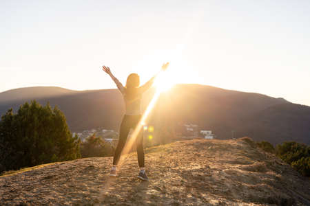 Woman standing, looking on sunrise in mountains