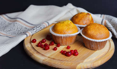 beautiful baking muffin cupcakes on a wooden board with red currant berriesの写真素材