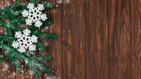 holiday snowflakes and snow with branches of Christmas trees on a wooden background texture for the new yearの写真素材