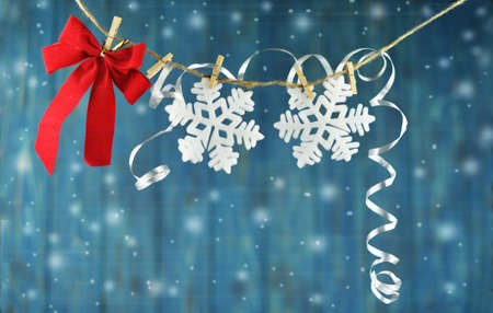red bow and snowflake on a rope with clothespins on a blue beautiful background with a bokeh on a...
