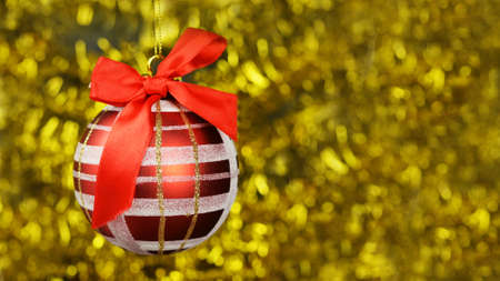 red festive bright decor toy ball with a red bow and pattern on a Christmas tree on a blurred background with a bokeh on a new yearの写真素材