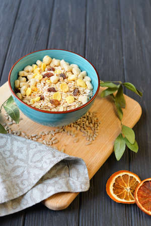 morning healthy breakfast, dietary meal porridge oatmeal muesli with raisins on a board with orange...