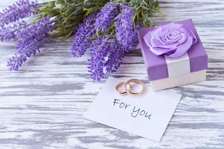 greeting card with lilac flowers lavender with gift box with training rings for the wedding on the...