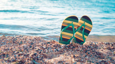 shoes flip flops, beach accessories with yellow and green on the beach of the ocean on the sandの写真素材